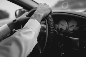 man holds his hands on the steering wheel, drives a car, black and white image