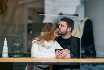 Dating in a cafe. Beautiful smiling girl with her boyfriend sitting in a cafe enjoying in coffee and conversation.