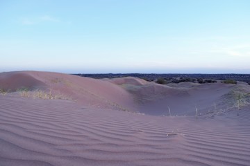 Purple sand dunes in the desert at dusk, a few minutes after sunset.