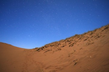 Fototapeta na wymiar Nightfall on the desert. The first stars can be seen in the deep blue sky.
