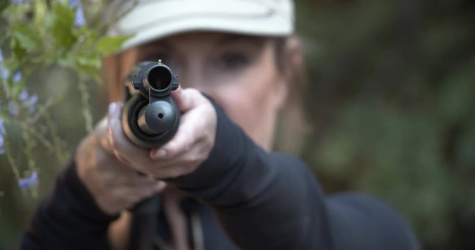 Woman aiming shotgun shallow depth of field.