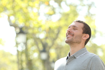 Happy casual man breathing fresh air in a park