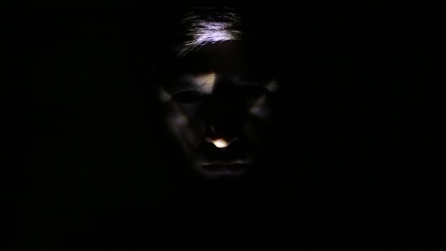 Dark portrait of creepy face selected with light.