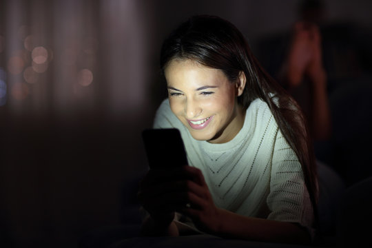 Happy Girl Checking Phone In The Night With The Face Lit