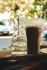 cup of coffee, a book, and a glass on the table and chair
