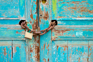 Beautiful weathered wooden door chained and locked with a big padlock.