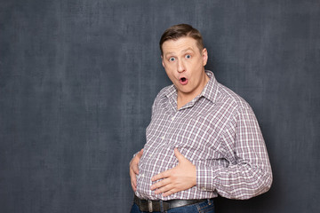 Obraz premium Portrait of surprised shocked man touching his big fat stomach