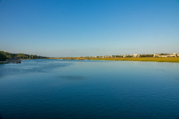 A saltwater creek at high tide in late afternoon sun and the houses that border it.