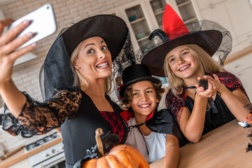 Happy young family taking selfie in Halloween decorated kitchen