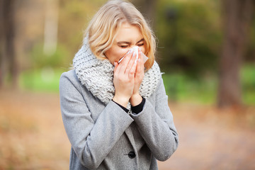 Woman portrait outdoor sneezing because cold and flu - obrazy, fototapety, plakaty