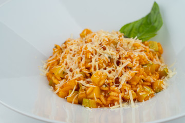 Close up of orange squash vegetables risotto with basil and parmesan cheese isolated on white flat lay