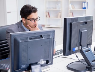 Businessman sitting in front of many screens