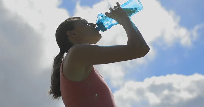 Young woman drinking bottle of water outdoors