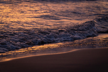 Orange sunset landscape with sea and beach sand. Sun reflection in foamy sea.  Cinematographic image. Romantic evening seascape with sunset. Exotic nature landscape