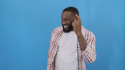 A cheerful man looks slyly at the camera and shows a gesture cleverly. 4K