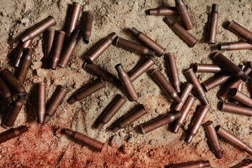 Pile of bloody rifle gun shells laying on battlefield.