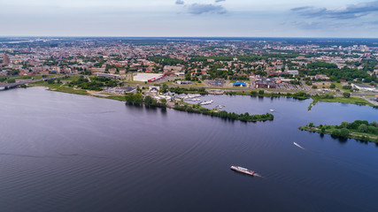 Fototapeta premium Tourist ship travels down the river Daugava in Riga, Latvia. Captured from above with a drone.