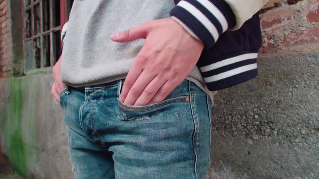 Person puts hands in pocket close-up 4K. Close up dolly slide of male person hands in focus.