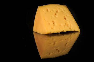 big wedge of hard porous yellow cheese with holes