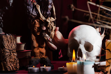 Female witch hand sitting at a table with skull and candles.