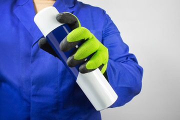 Worker in blue outfit and gloves holding bottle.