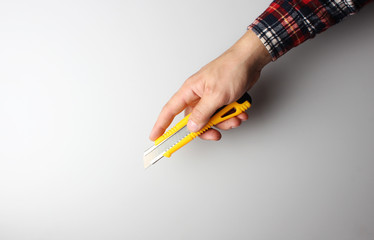 office knife in hand on a gray background