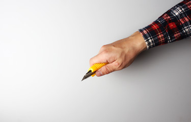 office knife in hand on a gray background