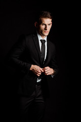 Fototapeta na wymiar confident businessman touching formal wear isolated on black