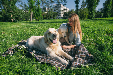 Girl with two golden retriever dogs in a park
