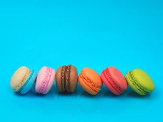 Colorful french macarons (macaroons) cake,  delicious sweet dessert on blue background with copyspace, food background concept.