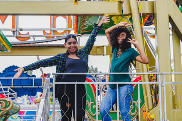 Obraz na płótnie Canvas Two young black girls, in ferris wheel, sharing and enjoying a summer day, lifestyle portrait