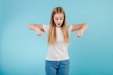 Fototapeta premium cheerful blonde woman pointing fingers down isolated over blue