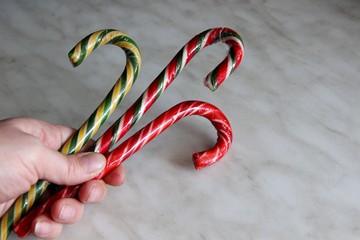 three candy canes holds in hand. three multi-colored lollipops canes clutched in the hand of the woman