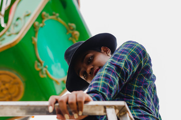 young girl of black color, laughing hair in ferris wheel, sitting enjoying a summer day, lifestyle portrait