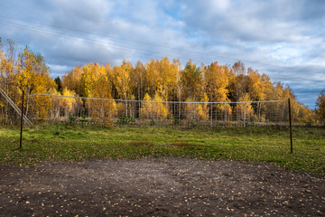 Volleyball net between metal poles against the backdrop of an autumn forest.