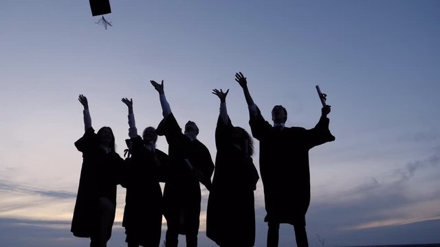 Silhouette of Graduating Students Throwing Caps In The Air.