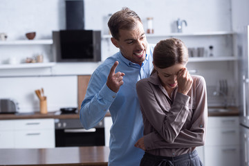 aggressive man in shirt screaming at crying wife during quarrel