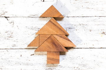 Tangram puzzle in christmas or pine tree shape on old white wood background