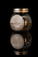 aromatic pepper peas in round glass jar isolated on black