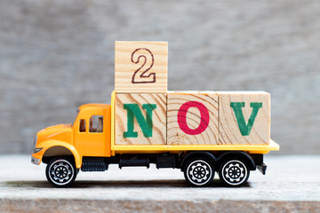 Truck hold letter block in word 2nov on wood background (Concept for date 2 month November)