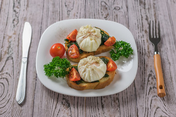 A knife and fork next to a bowl of poached eggs and toasted bread.