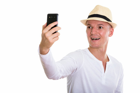 Studio shot of young happy man smiling while taking selfie pictu