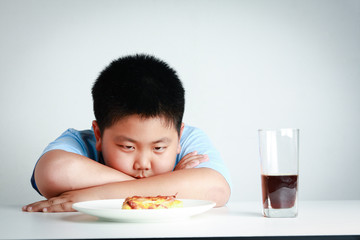 The fat Asian boy looked at the pizza with so much desire to eat. Child health concept