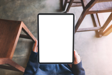 Top view mockup image of a woman holding black tablet pc with blank white screen while sitting in...