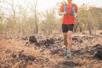 Healthy young man running on mountain trail in morning. Young man jogging on country path. Hiking or trail running man in mountains. © Sirichai
