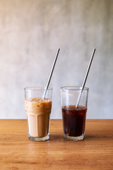Two glasses of iced coffee with stainless steel drinking straw on wooden table