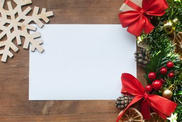 Christmas background with decorative composition of green tinsel, dried oranges, red berres, pine cone, gift with red bow and stars on wooden board. Happy new year.