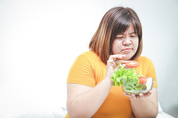 Fat Asian women eat fresh vegetables to lose weight. At the bed in her room