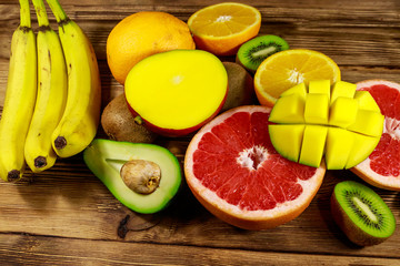 Assortment of tropical fruits on wooden table. Still life with bananas, mango, oranges, avocado, grapefruit and kiwi fruits