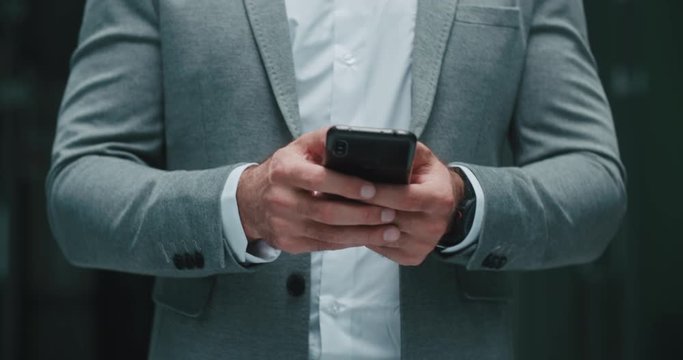 Closeup shot of businessman walking in office hall dealing with problems on his phone, chatting and talking - modern business concept 4k footage